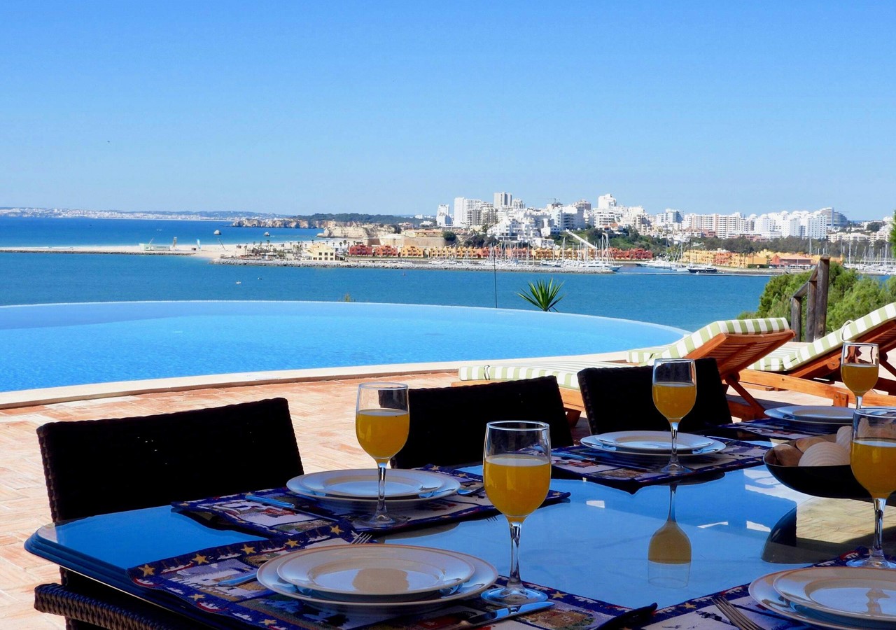 Dining area with view over the pool and sea in magnificent holiday home